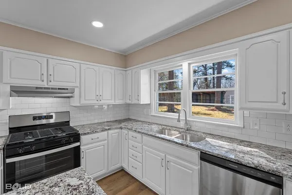 a kitchen with granite countertop a sink stainless steel appliances and cabinets