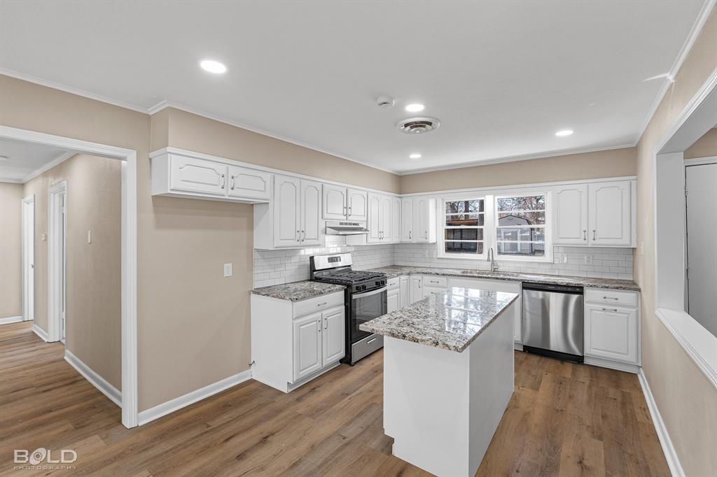 1211 Lee Street Benton, LA 71006 - Photo 15 of 39 a kitchen with stainless steel appliances granite countertop hardwood floor sink stove and wooden cabinets