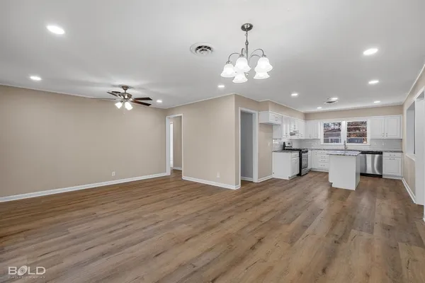 a view of a room with wooden floor and kitchen view