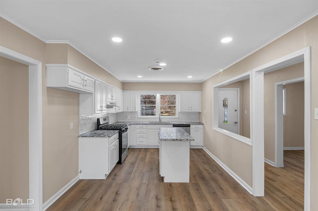 1211 Lee Street Benton, LA 71006 - Photo 9 of 39 a kitchen with white cabinets and wooden floor