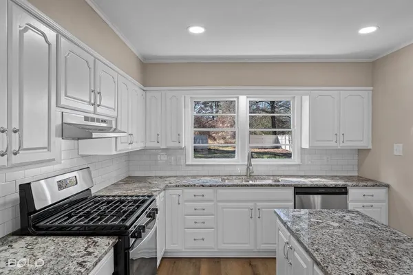 a kitchen with stainless steel appliances granite countertop a stove and cabinets