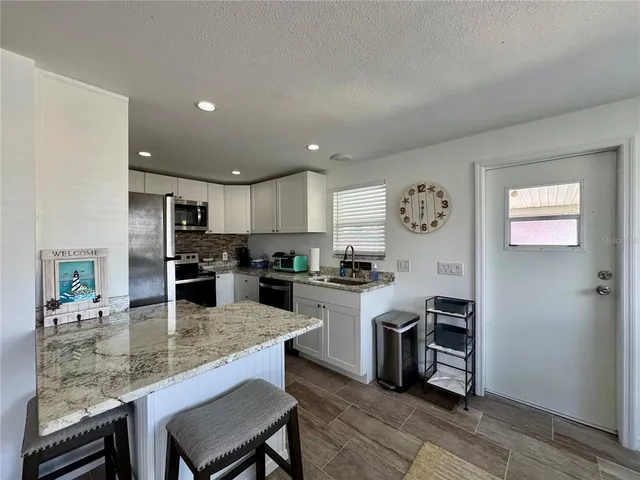 a kitchen with stainless steel appliances kitchen island granite countertop a table chairs microwave and sink