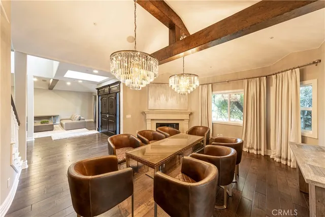 a kitchen with stainless steel appliances kitchen island granite countertop a stove a refrigerator a sink a dining table and chairs with wooden floor