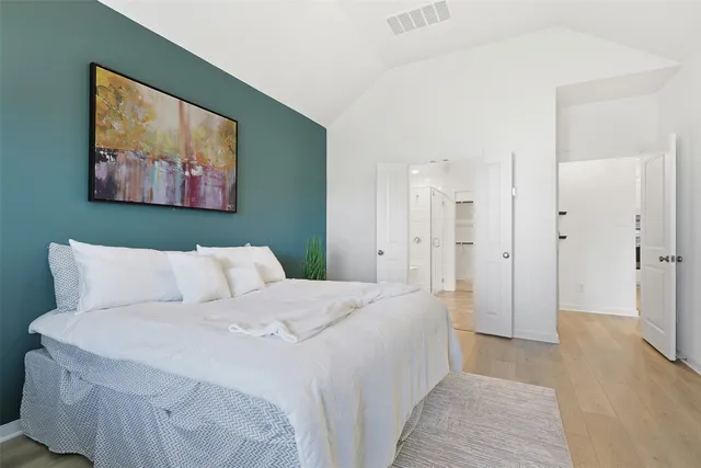 a spacious bedroom with a bed and a painting on the wall