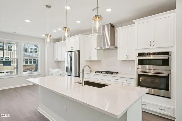a kitchen with stainless steel appliances granite countertop a sink a stove and a refrigerator