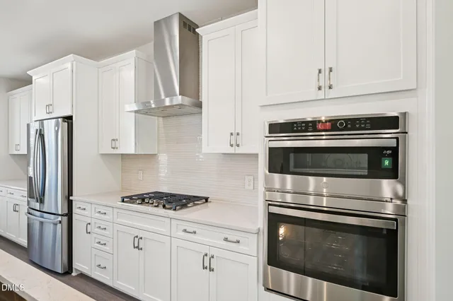a kitchen with stainless steel appliances granite countertop white cabinets and a stove a refrigerator with white countertops