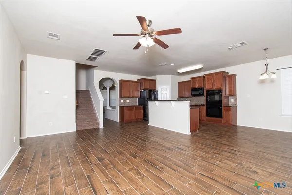 a view of a kitchen with a refrigerator wooden floor and a ceiling fan