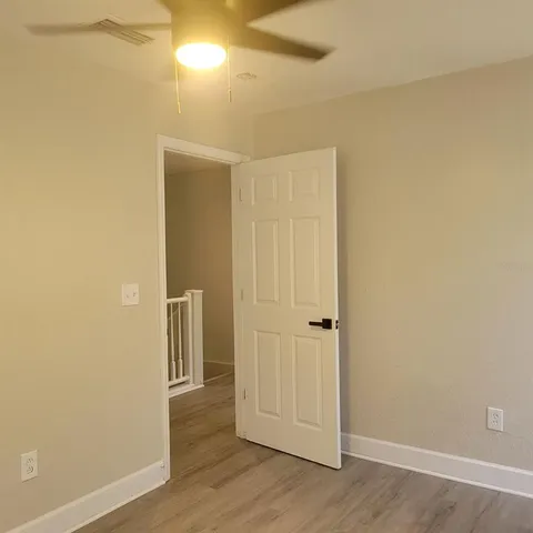 an empty room with a fan & a ceiling fan