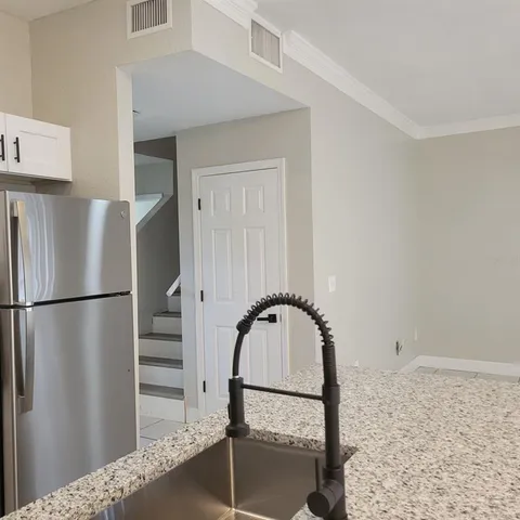 a kitchen with granite countertop a refrigerator and a stove top oven