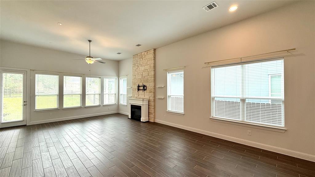 601 C-Bar Ranch Trail, Unit 27 Cedar Park, TX 78613 - Photo 9 of 29 Spacious living area featuring wood-finish tile flooring, a stone-clad fireplace with white mantel, a vaulted ceiling, and recessed lighting