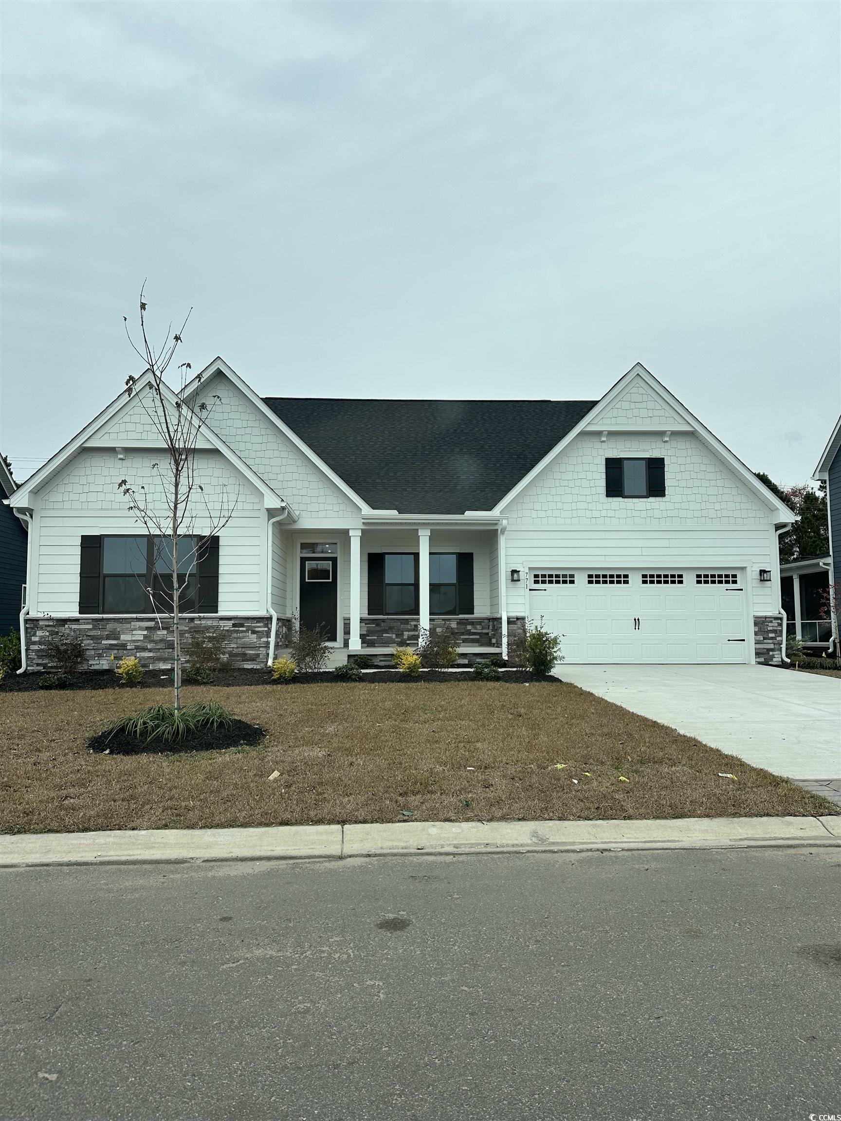 771 Indigo Bay Circle Myrtle Beach, SC 29579 - Photo 1 of 1 Craftsman house with stone siding, covered porch, concrete driveway, a garage, and a shingled roof