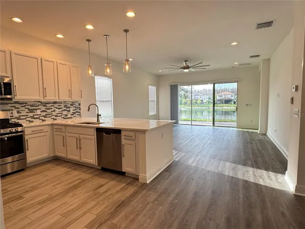 a large kitchen with stainless steel appliances a large counter top a stove a sink and a large window