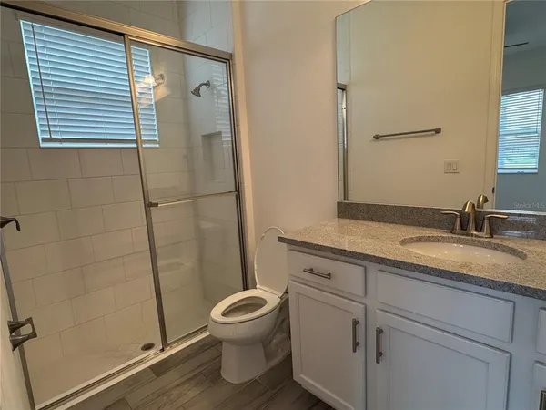 a bathroom with a granite countertop sink toilet and shower