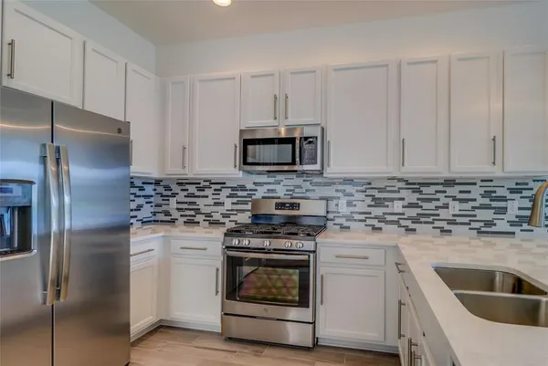 a kitchen with white cabinets and stainless steel appliances