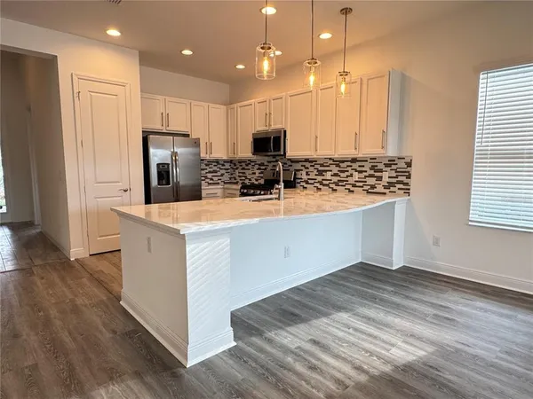 a kitchen with stainless steel appliances kitchen island granite countertop a refrigerator and a stove top oven