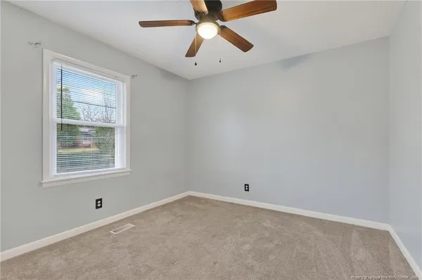 an empty room with a window and a fan
