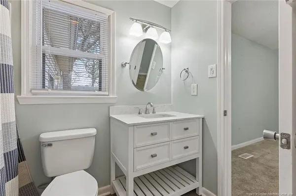 a bathroom with a granite countertop toilet a sink and a mirror