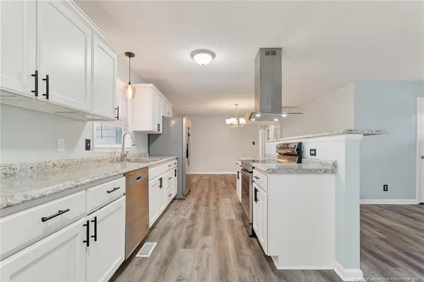 a large kitchen with a lot of counter space and wooden floor