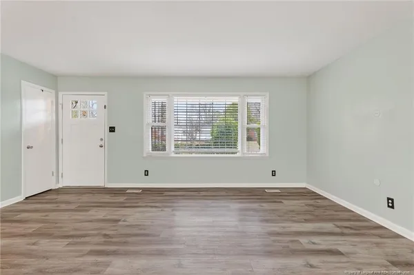 a view of an empty room with wooden floor and a window