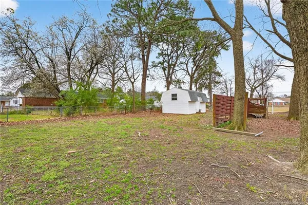 a backyard of a house with large trees and parked