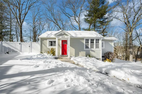 a view of a white house with a large tree and plants