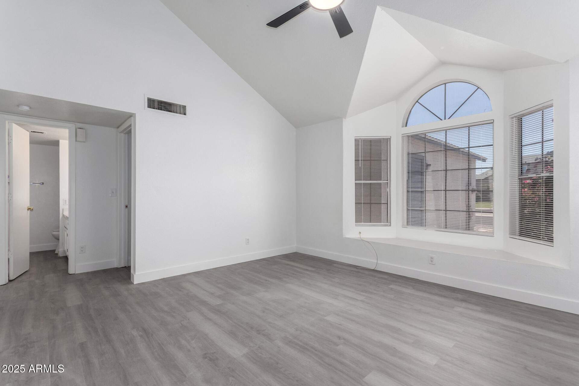 4162 East Wayland Road Phoenix, AZ 85040 - Photo 4 of 36 an empty room with wooden floor fan and windows