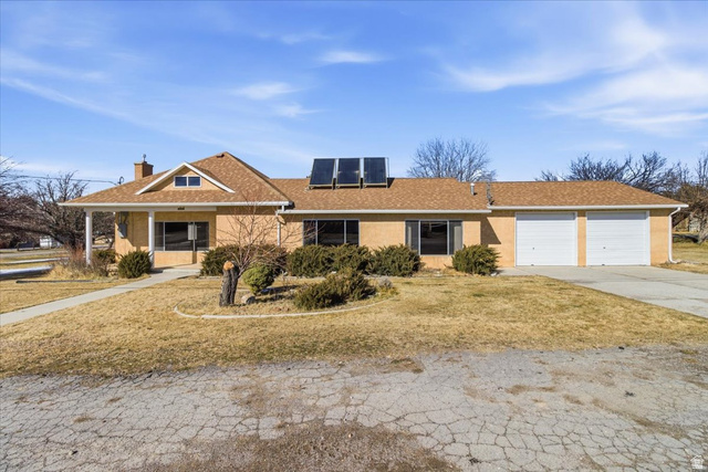 217 East 400 South Spring City, UT 84662 - Photo 61 of 71 Ranch-style house with solar panels, a front yard, a chimney, driveway, and a garage