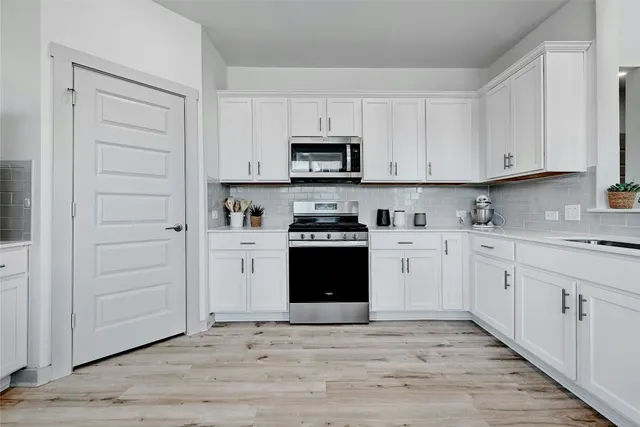 a kitchen with granite countertop white cabinets and stainless steel appliances