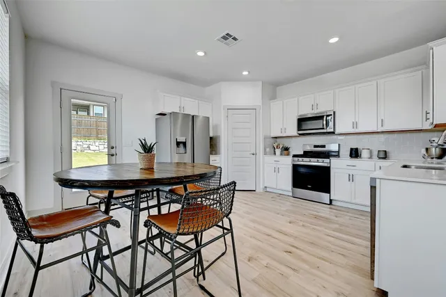 a kitchen with a table chairs a sink dishwasher stove and cabinets with wooden floor