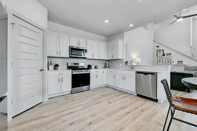 a kitchen with stainless steel appliances granite countertop a stove top oven a sink dishwasher and a refrigerator with wooden floor