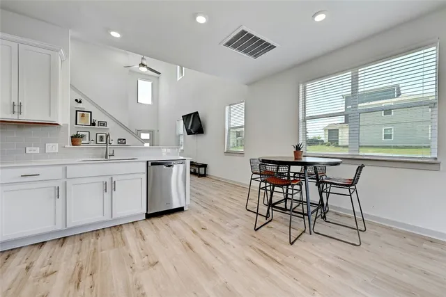 a kitchen with a table chairs wooden floors and a view of living room