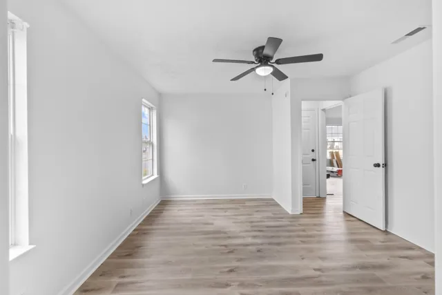 a view of empty room with wooden floor and ceiling fan