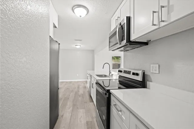 a kitchen with stainless steel appliances granite countertop a stove a sink and a microwave