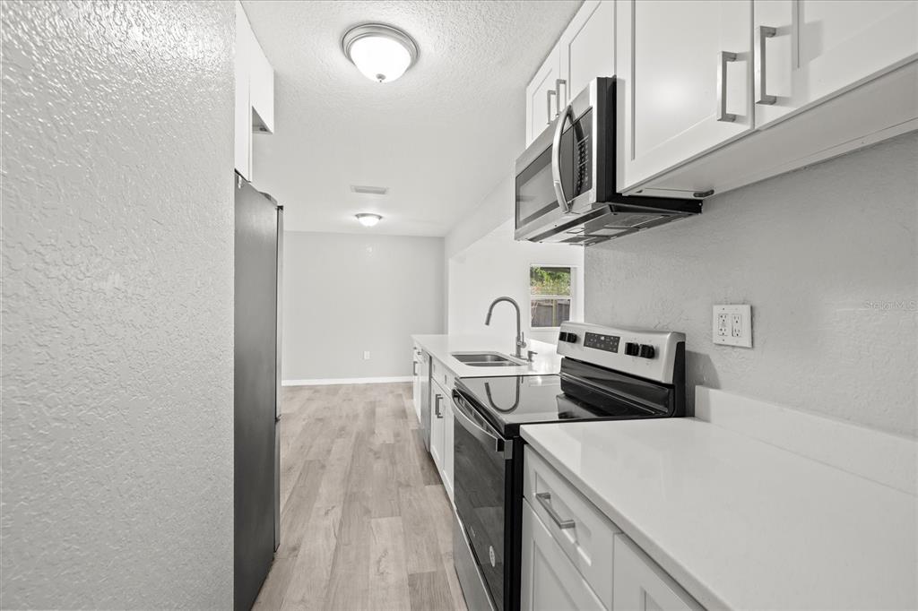 7445 Daggett Terrace New Port Richey, FL 34655 - Photo 14 of 35 a kitchen with stainless steel appliances granite countertop a stove a sink and a microwave