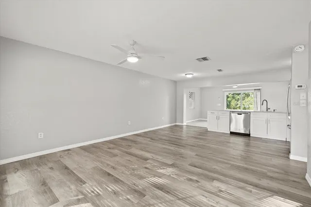 a view of an empty room with a window and wooden floor