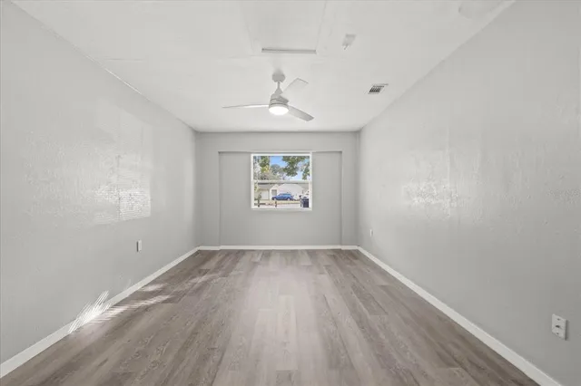 an empty room with wooden floor chandelier and windows