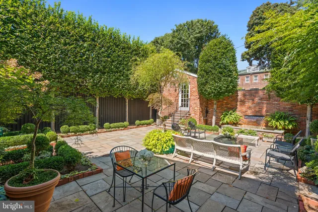 a view of a patio with couches table and chairs potted plants and large tree