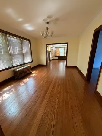 a view of an empty room with wooden floor and windows