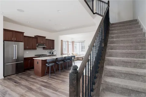 a kitchen with stainless steel appliances granite countertop a refrigerator a stove top oven a sink dishwasher and white cabinets with wooden floor