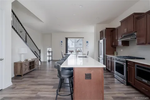 a kitchen with stainless steel appliances a table chairs stove and wooden floor