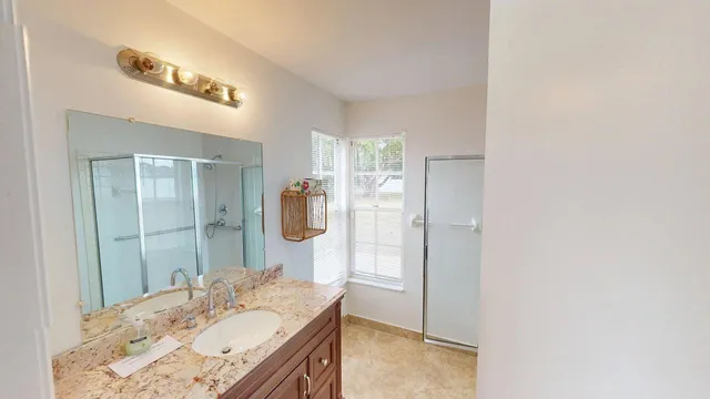 a spacious bathroom with a granite countertop sink a mirror and a shower