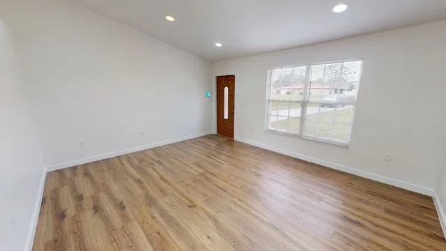 an empty room with wooden floor and windows