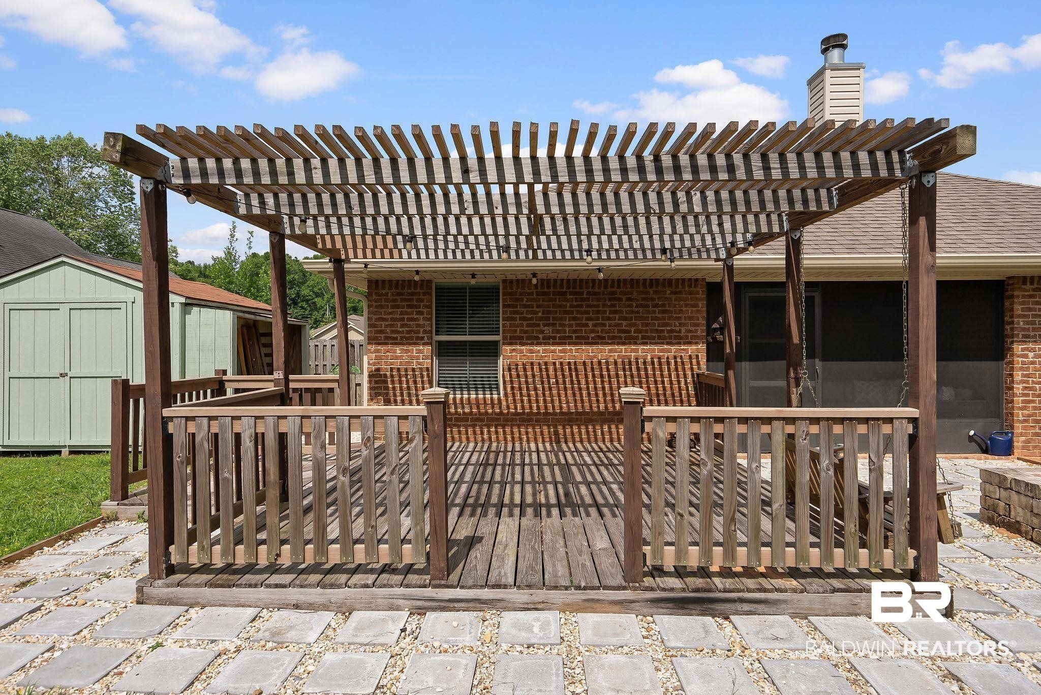 22076 Garland Loop Silverhill, AL 36576 - Photo 21 of 27 Expansive wood-finish deck featuring a slatted wood pergola, wood-finish railing, and a flagstone patio