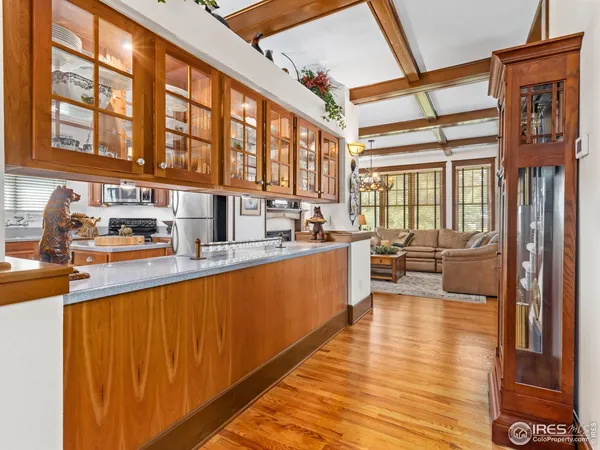 a large white kitchen with kitchen island granite countertop a large window a sink and stainless steel appliances