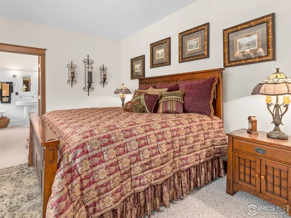 a bedroom with a bed a lamp and paintings on the wall