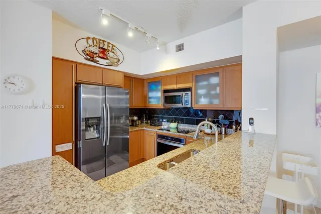 a kitchen with stainless steel appliances granite countertop a refrigerator a stove top oven a sink and dishwasher