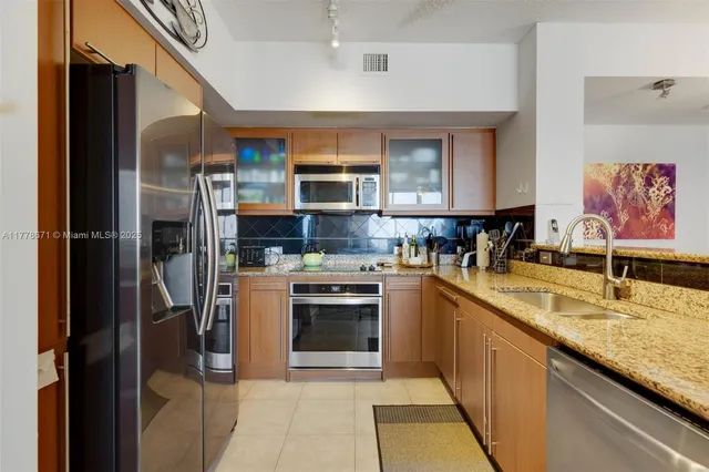a kitchen with stainless steel appliances granite countertop a refrigerator and a sink