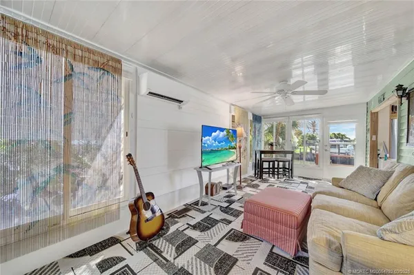 a living room with furniture a chandelier and a dining table with wooden floor