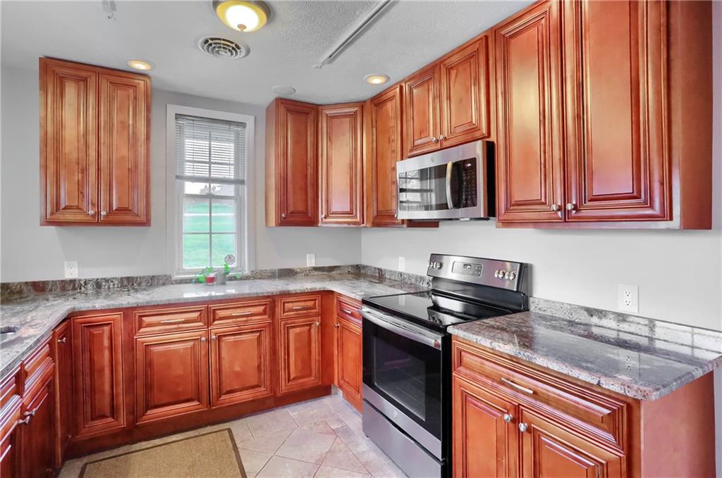 110 Oakville Road Beaver Falls, PA 15010 - Photo 17 of 48 a kitchen with stainless steel appliances granite countertop wooden cabinets a stove a sink and dishwasher