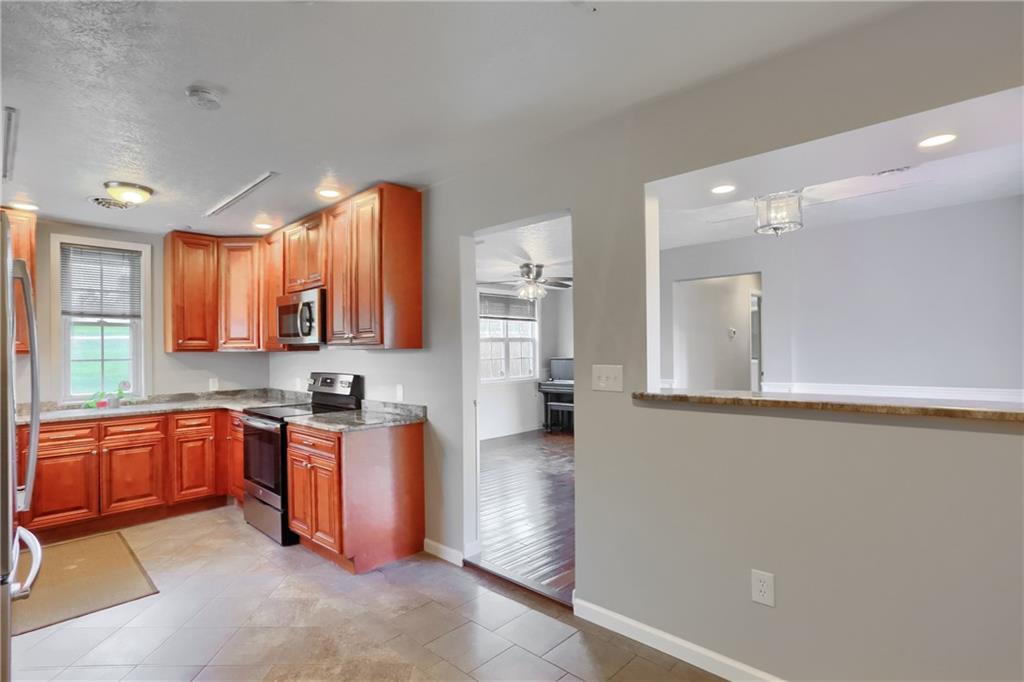 110 Oakville Road Beaver Falls, PA 15010 - Photo 22 of 48 a large kitchen with stainless steel appliances granite countertop a stove a sink dishwasher and a microwave oven with white cabinets